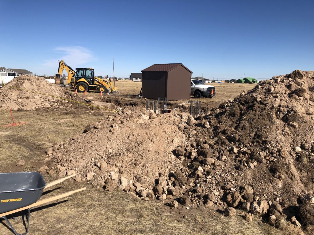 Construction job site with mounds of dirt, wheel barrows, and machinery